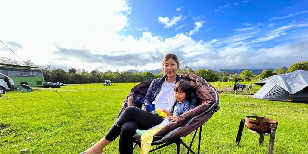 Mum and toddler sharing a camping chair at a Queensland campsite with mountain views